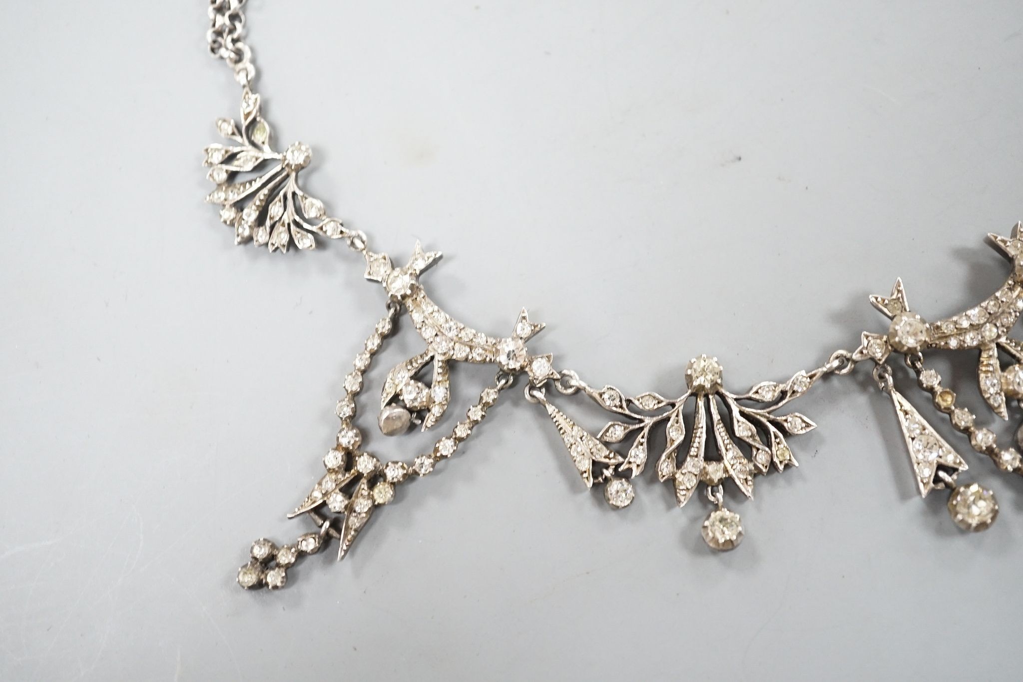 A 19th century white metal and paste set drop necklace, 37.5cm, in an associated gilt tooled fitted leather box.